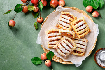 Homemade puff pastry pies filled with caramelized apples . green background. top view