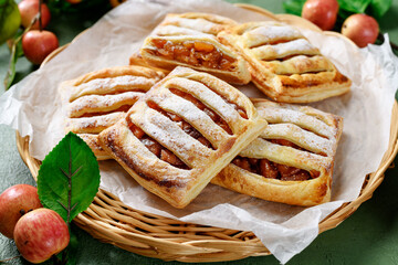 Homemade puff pastry pies filled with caramelized apples . green background © Nelea Reazanteva