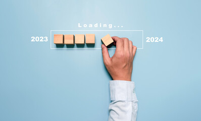 Businessman assembly wooden block in progress bar for loading new year 2023 to 2024 concept.