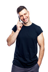 Smiling young man in a black t-shirt is talking on the phone. Isolated on white background. Vertical.