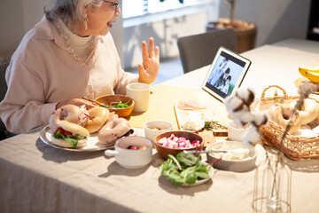 孫たちとのビデオ電話を楽しみながら食事をするおばあちゃん