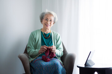 笑顔で編み物をするシニア女性のポートレート