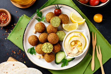 Plate of chickpeas falafel balls with hummus, vegetables  and lemon slices .Top view.