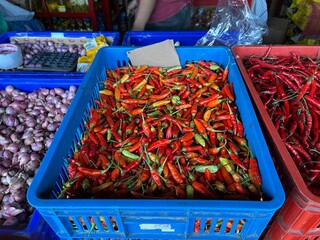 Pile of red chilies on a blue plastic basket being displayed in a Asian traditional market for sale