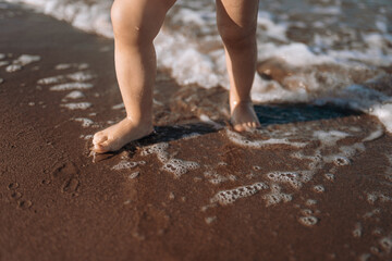 little child sea, girl in swimsuit joyful plays on the beach