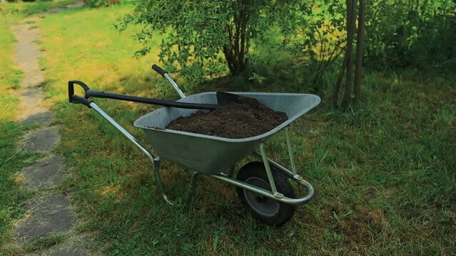 garden cart with earth and a shovel stands on the lawn