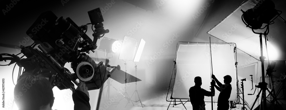 Wall mural Silhouette of video production behind the scenes or B roll or making of TV commercial movie that film crew team lightman and cameraman working together with director in big studio with pro equipments