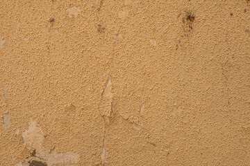 abstract background of an old shabby rough painted ocher wall close up