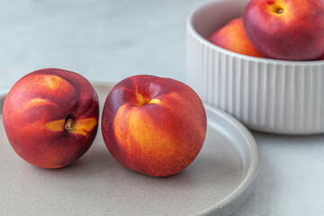 ripe sweet nectarines in a ceramic bowl on a white marble surface close up