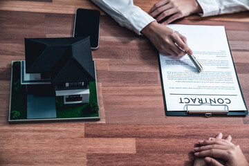 Top view buyer signs the loan contract paper with a pen on the desk as the completing the final...