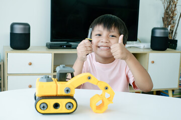 Adorable Asian kid thumbs up because he just finish assemble an excavator toy