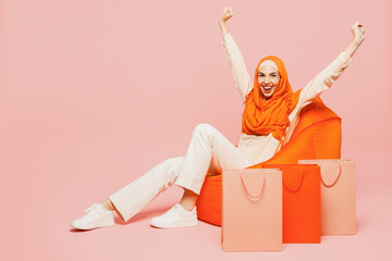 Full body winner young arabian asian muslim woman wear orange abaya hijab hold shopping package...