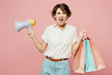 Young sad woman wear casual clothes hold shopping paper package bags scream in megaphone announces...