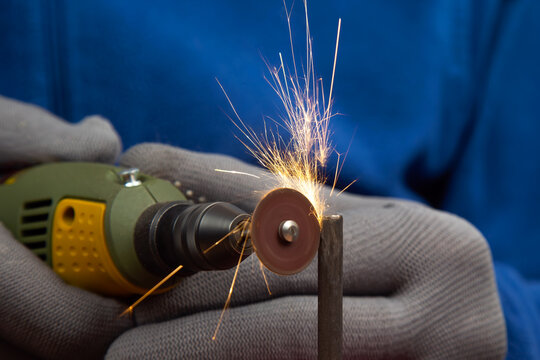 Worker processes metal with engraving drill close-up. The work of the dremel engraving electric tool. Industrial metal processing