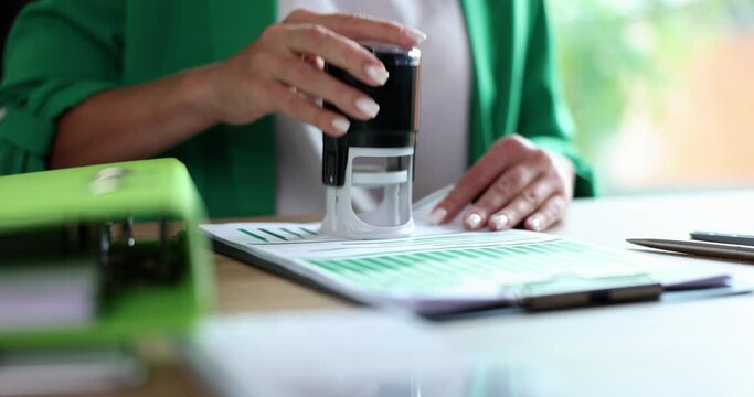 Businesswoman studying documents with graphs and putting seal on them closeup 4k movie slow motion. Official certification of important documents concept