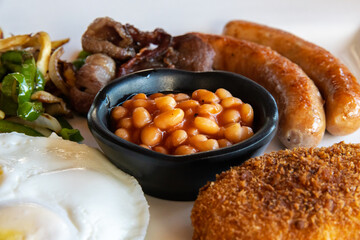 American Breakfast with Eggs, Sausages, Bacon, Beans, Hash Brown Potatoes and Sauted Vegetables