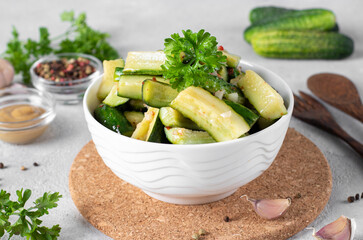 Pickled cucumbers slices with mustard, garlic and paprika in white bowl