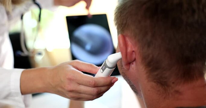 Doctor otorhinolaryngologist examining patient ear using modern digital otoscope closeup 4k movie slow motion. Diagnosis and treatment of otitis media concept