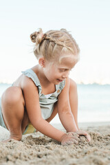 Fototapeta na wymiar Cute girl playing with sand on beach