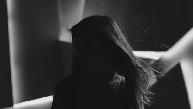 Close up portrait of pretty brunette female model . Beautiful attractive face of young woman . Hair flowing or blowing in wind . Face Changes Depending on the Lighting . Shadow and light movement . 