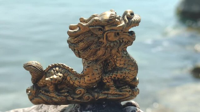 Figurine of a Chinese golden dragon on the seashore in summer.