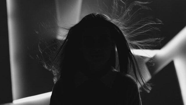 Close up portrait of pretty brunette female model . Beautiful attractive face of young woman . Hair flowing or blowing in wind . Face Changes Depending on the Lighting . Shadow and light movement . 
