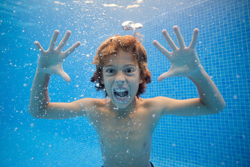 Crazy boy making grimace underwater of swimming pool