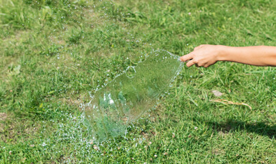 A boy waters the grass with a hose