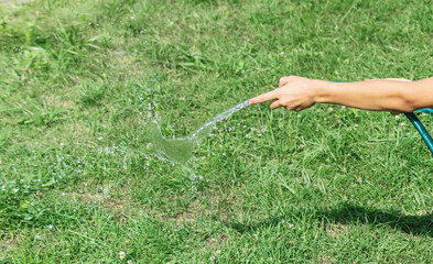 A boy waters the grass with a hose