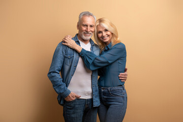 Portrait of smiling elderly couple friends posing on beige background