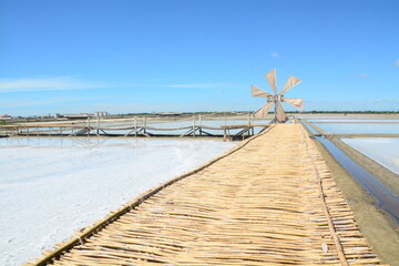 Windmills and bamboo bridges with a bright blue sky in the salt fields