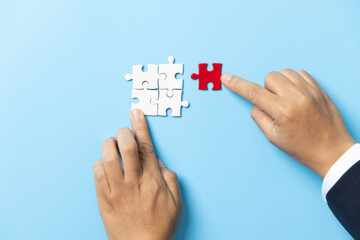 Two hands trying to connect couple puzzle piece on blue background. Teamwork concept. Closeup hand of connecting jigsaw puzzle.