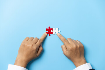 Two hands trying to connect couple puzzle piece on blue background. Teamwork concept. Closeup hand of connecting jigsaw puzzle.