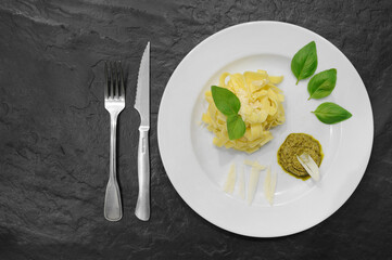 Pâtes au pesto et parmean dans une assiette sur fond d'ardoise
