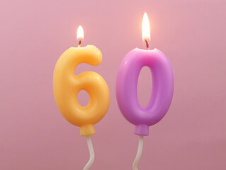 Air balloon shaped birthday candles burning on pink background. Number 60.