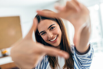 Fototapeta premium Beautiful smiling woman looking at camera while standing in living room at home.