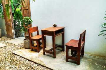 Fototapeta na wymiar Wood table and chairs in the garden. Vintage square wood table and two chair in ornamental garden.