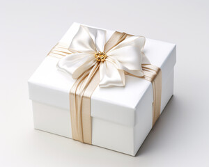 Obraz premium A white gift box with a gold ribbon and bow on top on a plain white background.