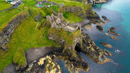 Picturesque landscape featuring the Dunluce Castle on a hill overlooking the shimmering blue water