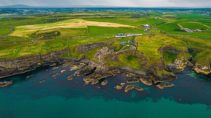 Aerial view of a scenic, green island in Ireland, featuring the Dunluce Castle