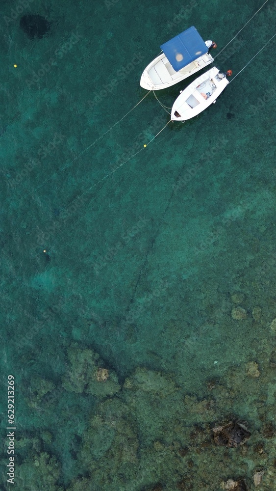 Sticker aerial view of boats in crystal clear blue ocean waters of corfu island in greece.