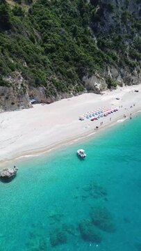 Vertical drone view over boats parked on an azure seacoast with forested cliffs in Corfu, Greece
