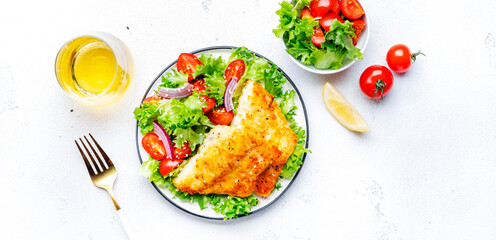 Fried white fish with salad from lettuce, cherry tomatoes and red onion with sesame seeds, white...