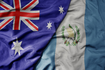 big waving realistic national colorful flag of australia and national flag of guatemala .