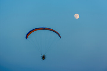 paragliding on blue sky with full moon