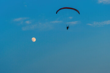 paragliding on blue sky with full moon