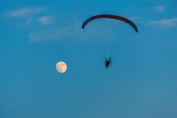 paragliding on blue sky with full moon