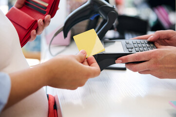 Close-up hands of a customer swiping a mockup golden credit card, making contactless payments using NFC technology.