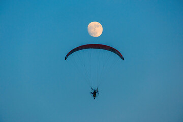 paragliding on blue sky with full moon