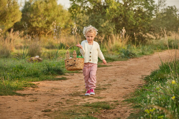 Funny girl with wicker basket walking on dirt road